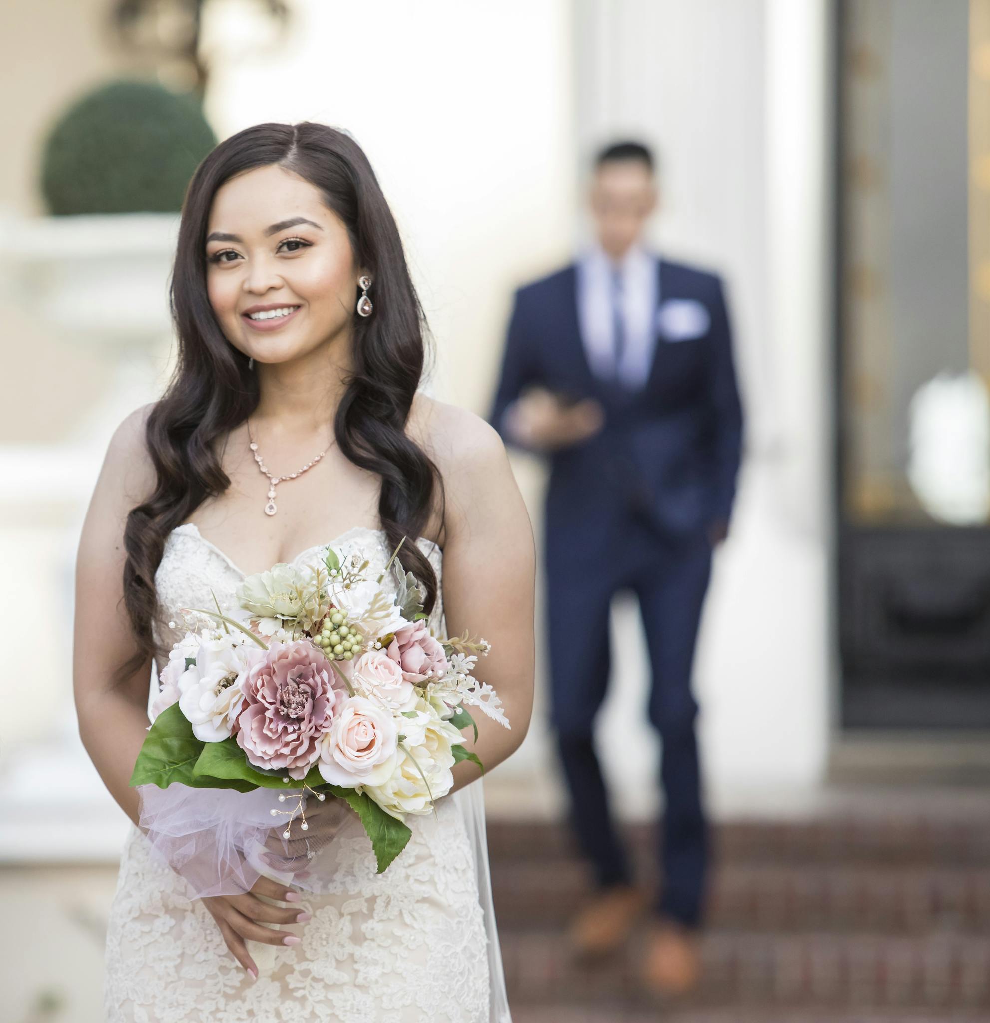 Smiling bride holding bouquet in a beautiful outdoor wedding portrait.